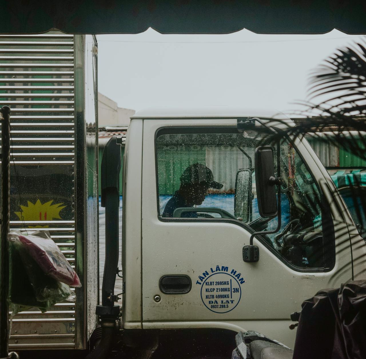 Side profile view of a truck driver inside cab during rain. Urban delivery concept.