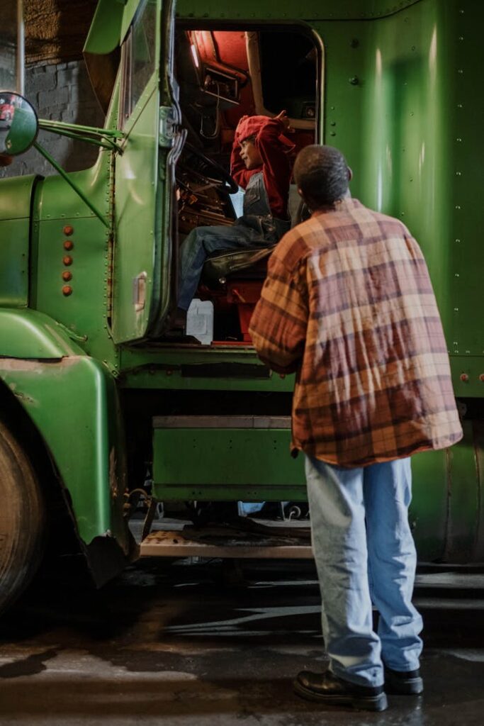 Two men collaborate on truck maintenance, showcasing teamwork and dedication.